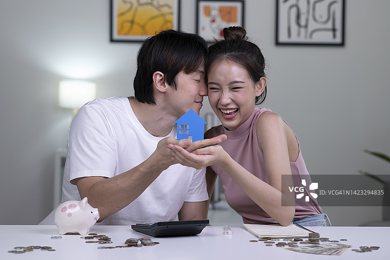 年轻的亚洲夫妇正在攒钱买房。图片素材