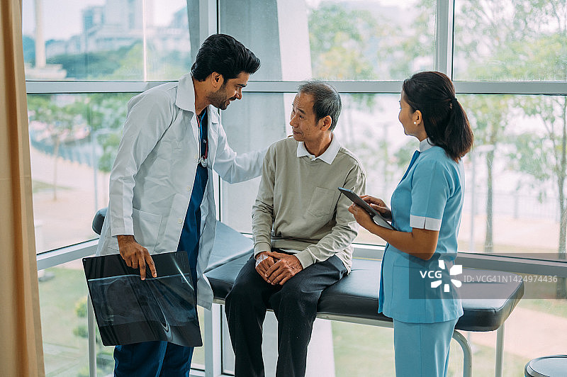 医生和病人正在交谈。成熟的亚裔印度医生在医疗诊所安慰年长的成年病人。图片素材