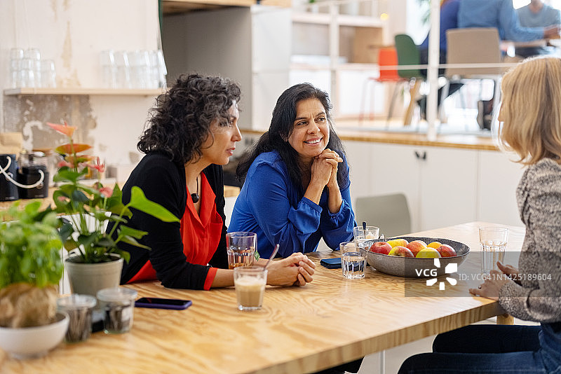 三名女商人在办公室自助餐厅喝咖啡休息时交谈图片素材