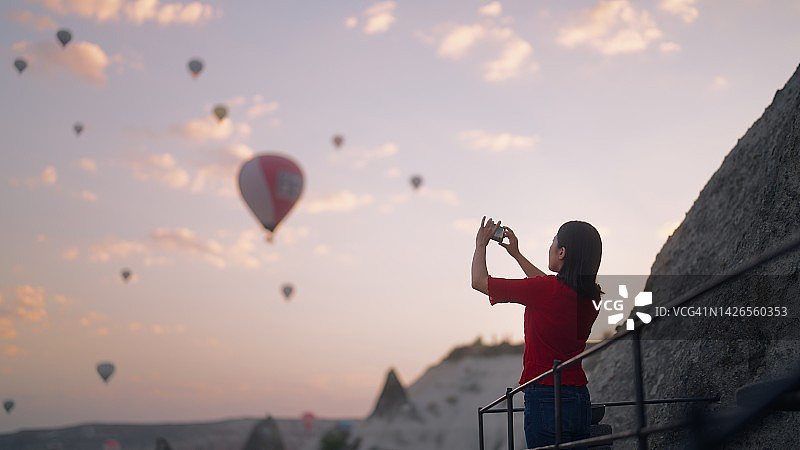 年轻女游客在酒店楼顶拍摄热气球图片素材