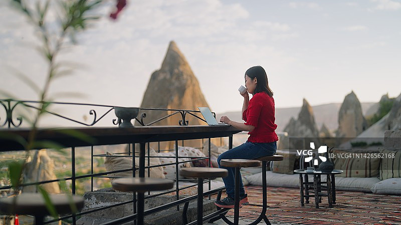年轻的女自由职业者游客使用她的笔记本电脑在酒店的屋顶露台图片素材
