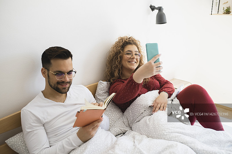 这是一对中年夫妇早上在床上使用智能手机的照片图片素材