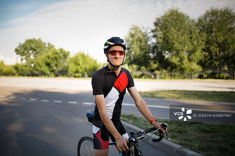 患有脑瘫的年轻人夏天在公园里骑自行车。图片素材