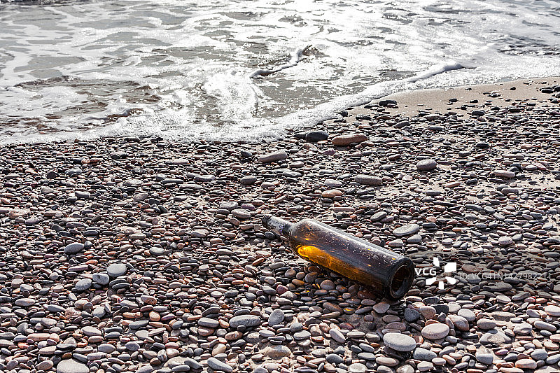 被遗弃在海滩上的空酒瓶。环境污染的概念。垃圾造成的生态问题。图片素材