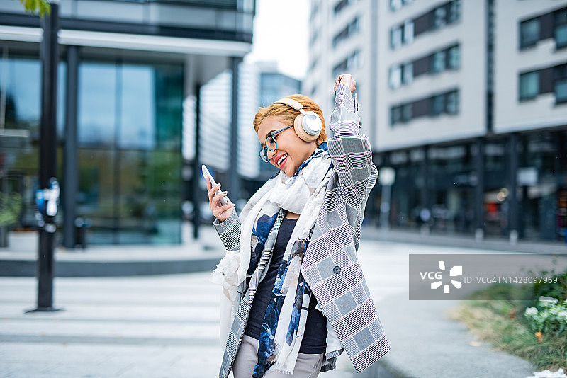 年轻女子在城市里戴着耳机听音乐图片素材