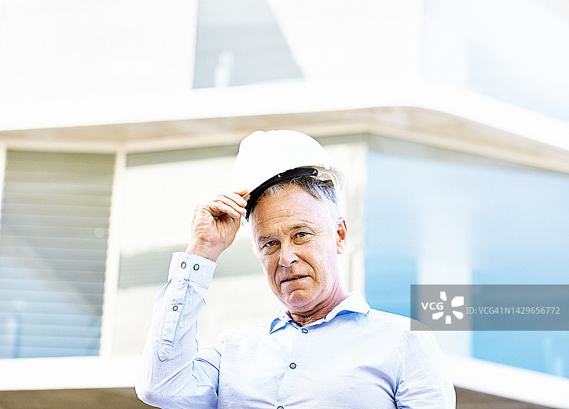 脱掉安全帽的英俊中年男子:建筑老板、建筑师或土木工程师图片素材
