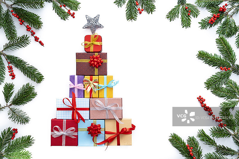 圣诞礼盒的形状与圣诞树和杉树和冬青浆果的边界框架孤立的白色图片素材