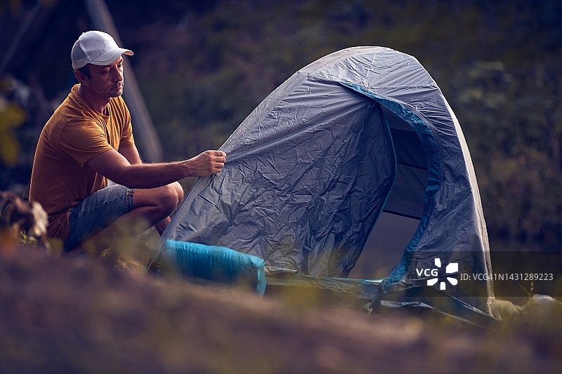 人们在大自然中露营，在森林河边搭起帐篷过夜。图片素材