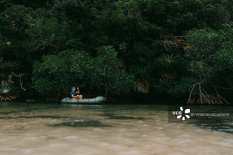日本冲绳石垣岛，一名男子划着皮划艇穿过红树林河图片素材