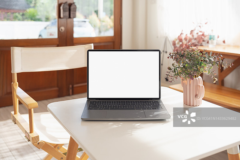 笔记本电脑空白屏幕在桌子上的咖啡馆背景。咖啡店桌子上黑屏的笔记本电脑模糊了背景图片素材