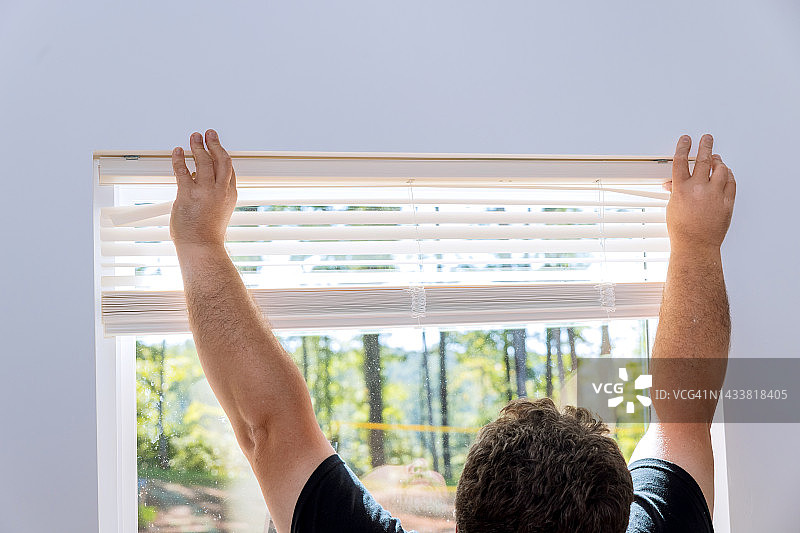 一个承包商在一所新建的房子上安装百叶窗图片素材