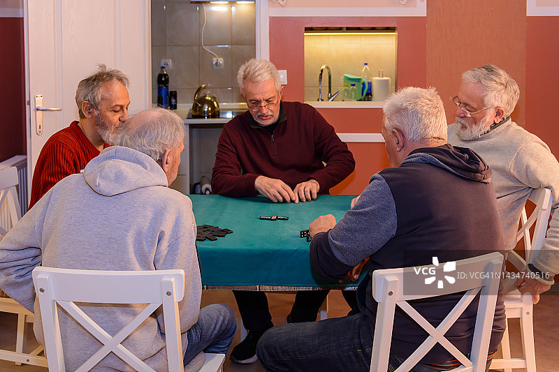 社交聚会上的年长参与者玩多米诺骨牌玩得很开心。图片素材