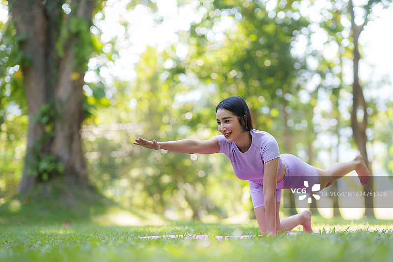 在公园里做瑜伽。年轻的亚洲女子在公园里练习瑜伽姿势。图片素材