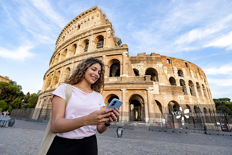 快乐的游客在罗马竞技场使用手机上的移动应用程序图片素材