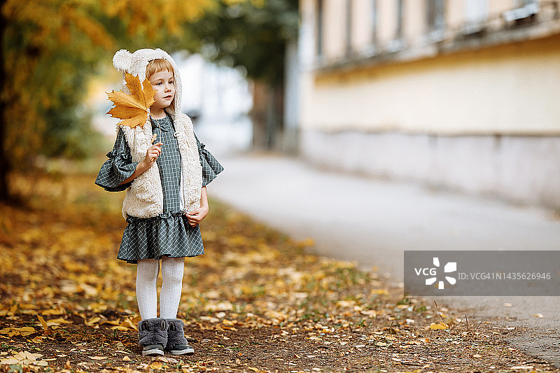 在秋天的街道上，穿着裙子的微笑的女孩图片素材
