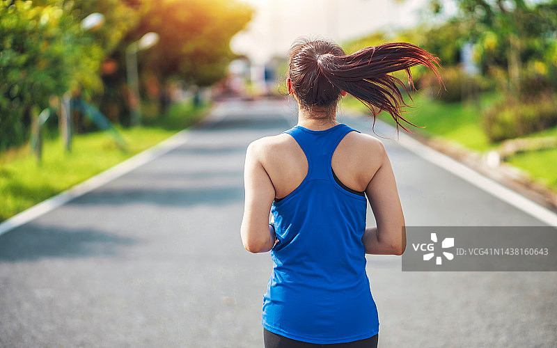 后视图年轻的健身运动妇女跑步者在公园里跑步。健康的健身妇女在户外慢跑。体育与健康概念图片素材