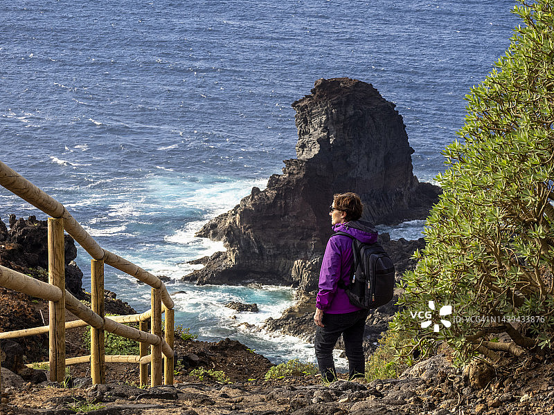 在拉帕尔马加那利岛的海边，一个女人走在山间小路上。图片素材