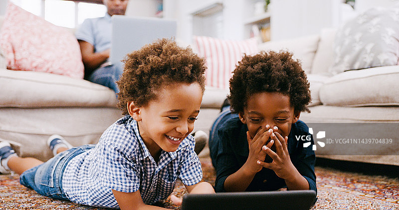 孩子们，在客厅的地板和平板电脑，看有趣的或教育视频，有趣的卡通或玩在线游戏。科技，互联网或黑人男孩玩地毯与手机应用一起图片素材