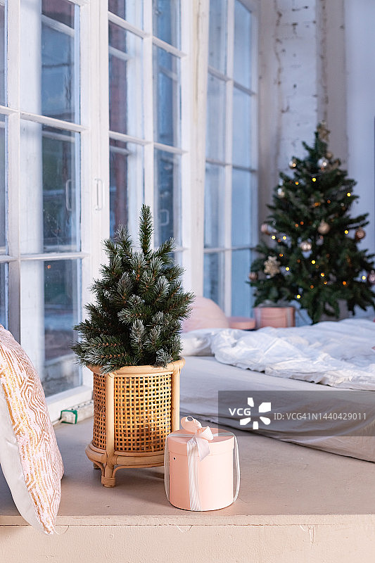 美丽的圣诞礼品盒在房间杉树附近的地板上。圣诞树上有彩色的球和礼物。为节日而装饰的屋子。图片素材