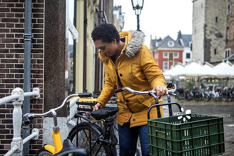 一个雨天在代尔夫特骑自行车上下班的黑人女商务女旅行者图片素材