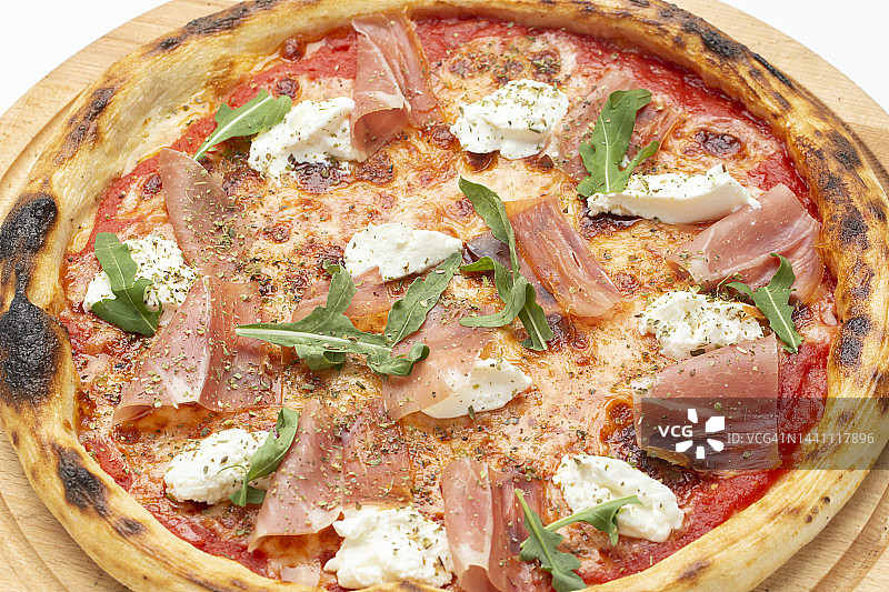美味的意大利披萨配火腿、奶酪、芝麻菜和西红柿。图片素材