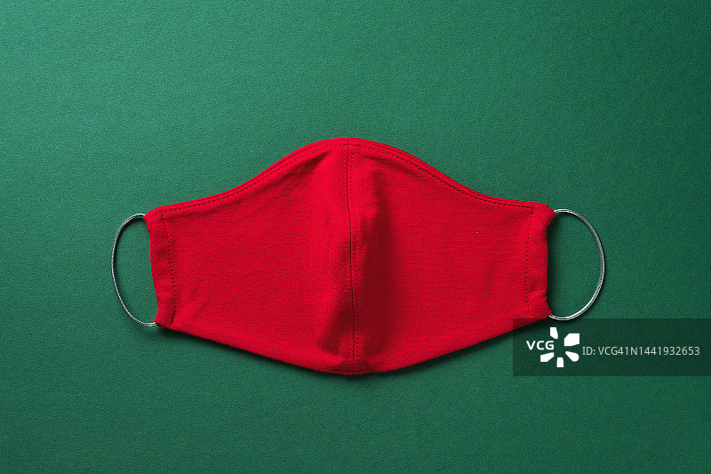 绿色圣诞背景下的红色医用口罩。预防和预防covid-19大流行的传播。预防病毒、感染和肺炎。快乐健康圣诞节的概念。图片素材