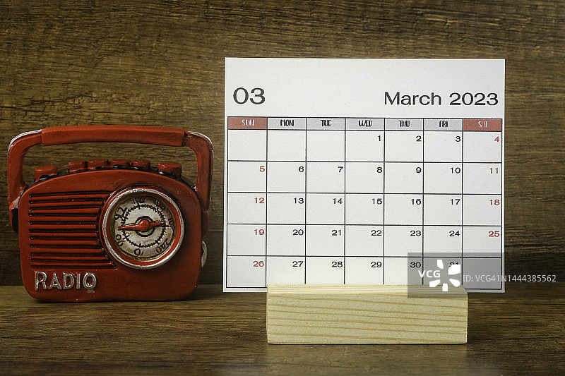 日历桌2023:3月是组织者计划和截止日期的月份，在木桌背景下放一台老式收音机。图片素材