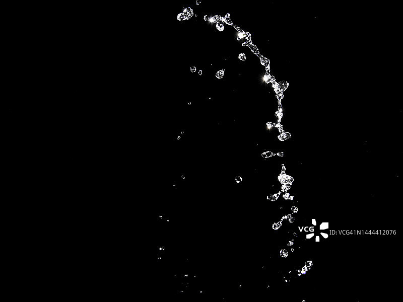 黑色背景上流动的水花和水滴。图片素材