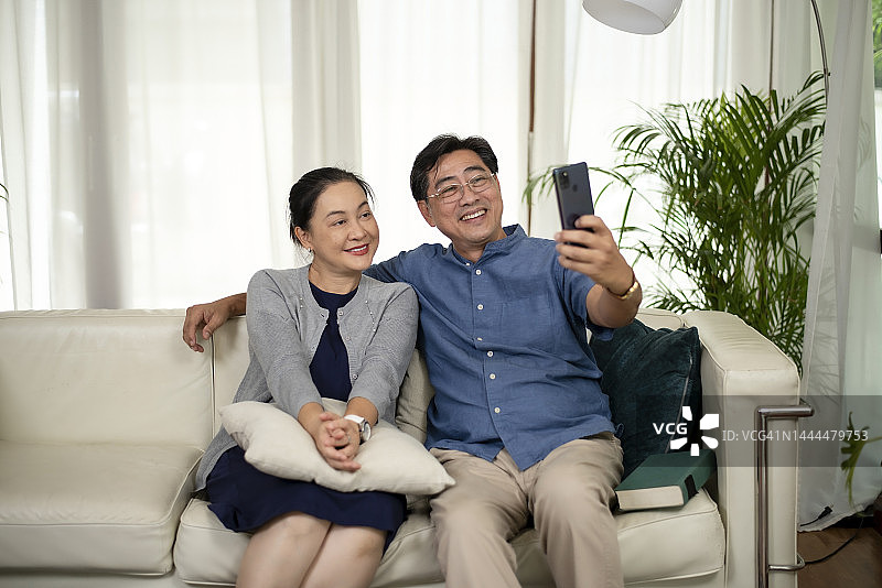 这两位老人正在用手机和家人愉快地打vdo电话，他们的脸上带着笑容。图片素材