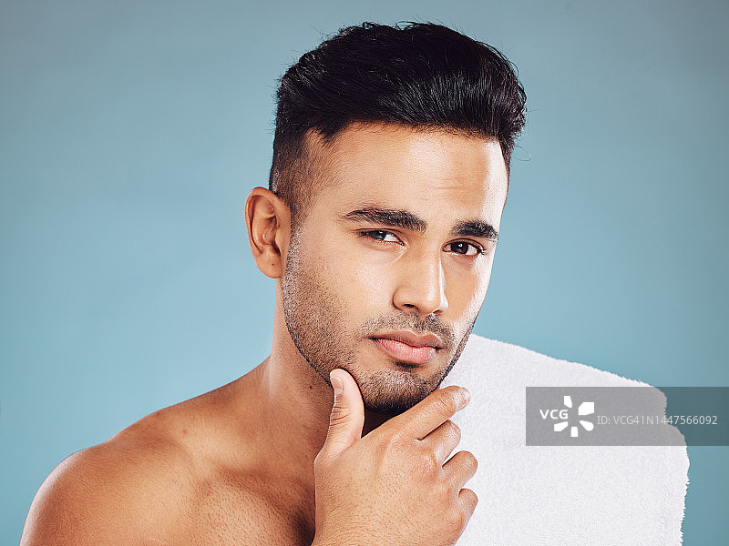 男士，手在脸上和护肤清洁或美容化妆品肖像在工作室。年轻的印度模特，健康的面部护理和身体皮肤排毒或健康的生活方式治疗蓝色背景图片素材