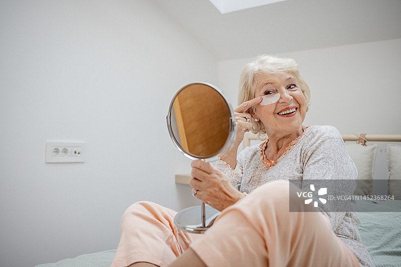 微笑的老年女性看着镜子里的自己图片素材