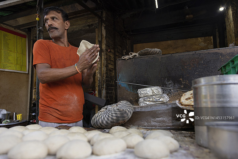 当地路边餐馆或达巴的厨师，用陶木烤炉或铁炉做面包或烤面包图片素材