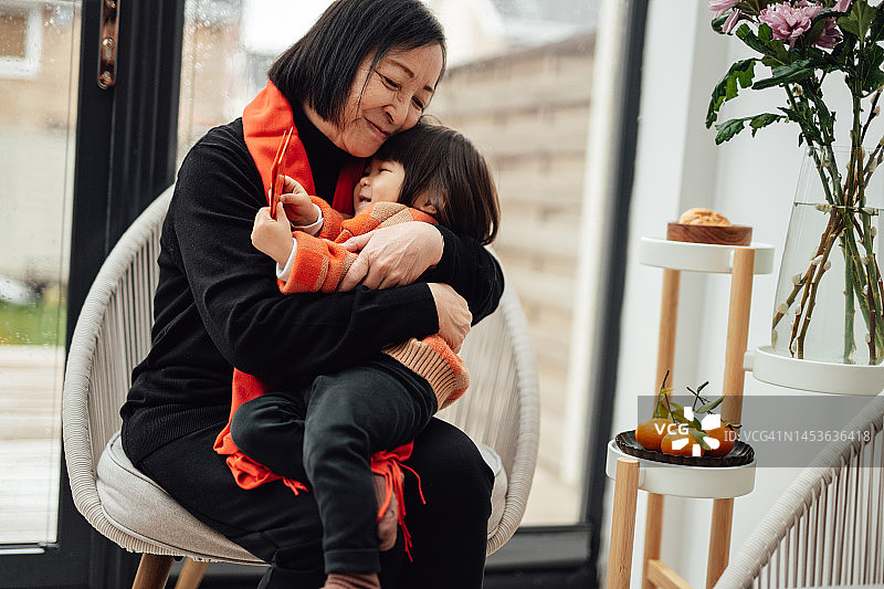 微笑的亚洲祖母拥抱她的孙女，在家里庆祝中国新年图片素材
