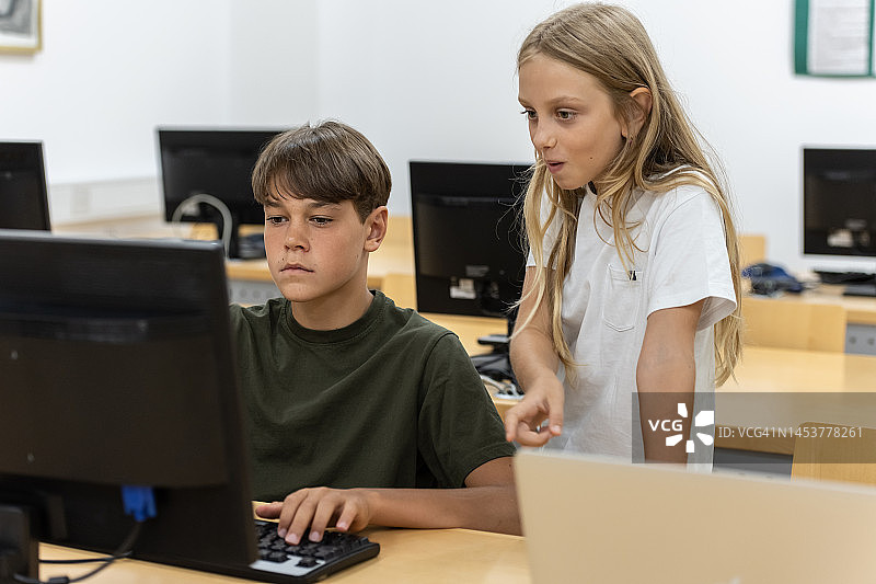 小学生在图书馆玩电脑。图片素材