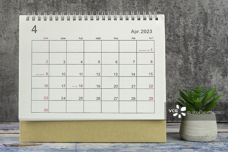 日历桌2023:4月是组织者计划和截止日期的月份，在混凝土墙背景下放置室内植物。图片素材