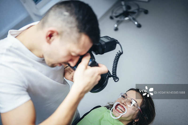 治疗结束后，牙医用相机拍照。图片素材