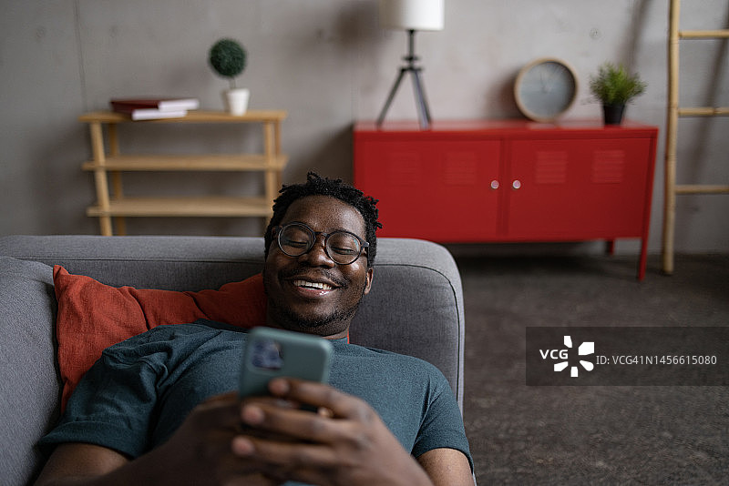 快乐的非裔美国成年男子在家里使用智能手机图片素材
