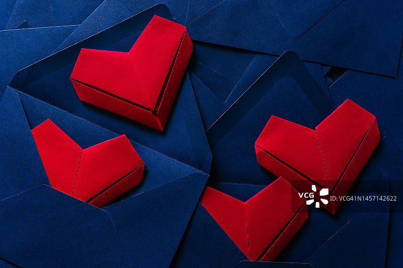 红纸心和蓝色信封，情书的想法，蓝色信封和红色的心溢出。图片素材