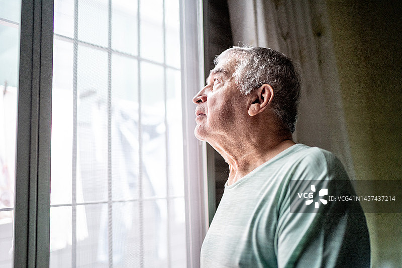 一位老人凝视着家里的窗户图片素材