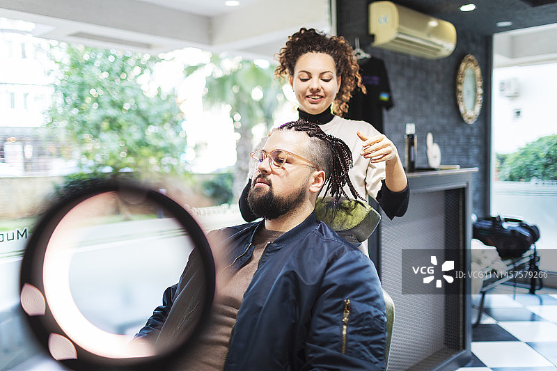 年轻的女理发师在理发店编织头发给客户图片素材