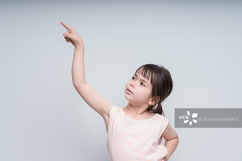 小女孩的肖像，手指朝上。摆着姿势的小孩把想法孤立在白黑板上。成功，聪明的想法，创新的想法和创新的技术理念图片素材