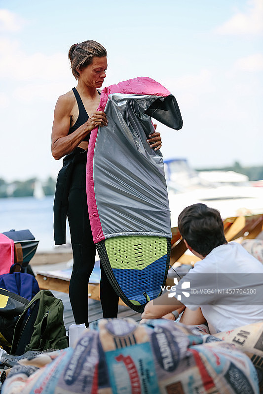 成年运动看起来女人准备水上滑板和拿出她的冲浪板图片素材