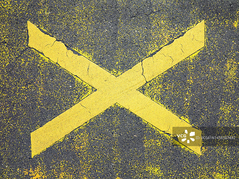 在巴黎的一条灰色柏油路上，字母X被涂成了黄色，并已被风化图片素材