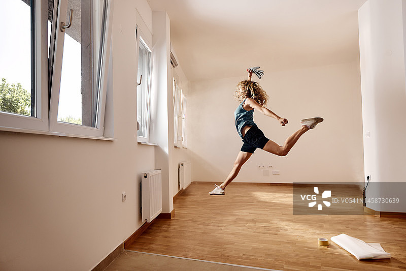 无忧无虑的女人在她的新公寓里跳跃。图片素材