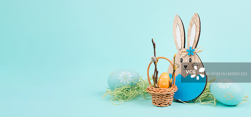 复活节兔子或兔子坐在柳条篮子旁边，篮子里装满了五颜六色的彩蛋，春暖花开图片素材