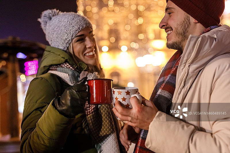 浪漫的情侣端着热红酒在圣诞市场欢呼图片素材