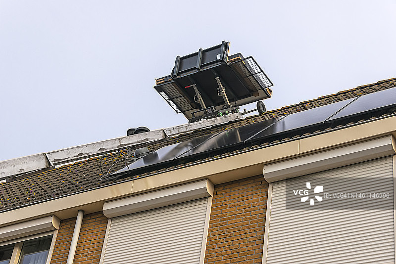 在屋顶安装太阳能电池板时，梯子上的移动平台图片素材