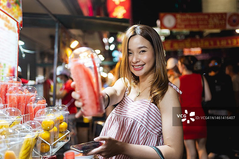 年轻的亚洲妇女在曼谷唐人街购买冰沙饮料图片素材