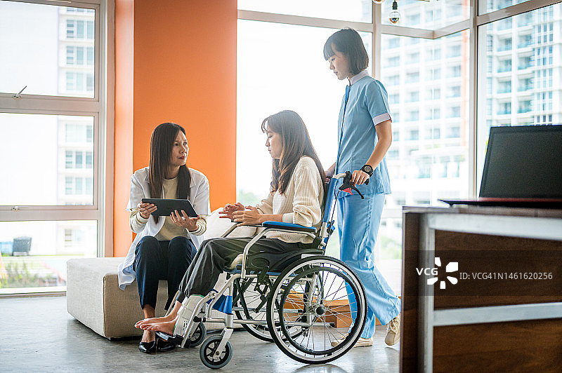 一名亚裔女医生在医院的数字平板电脑上展示她的病人结果图片素材