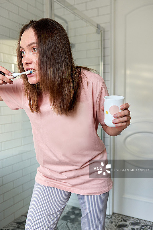 早上在浴室里穿着t恤刷牙的女人图片素材